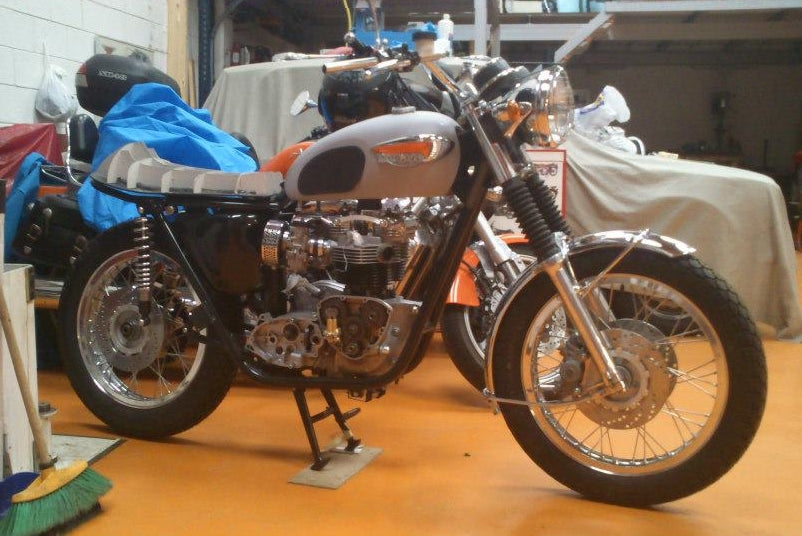 Triumph Bonneville T140 en proceso de restauración en taller con motor bicilíndrico visible